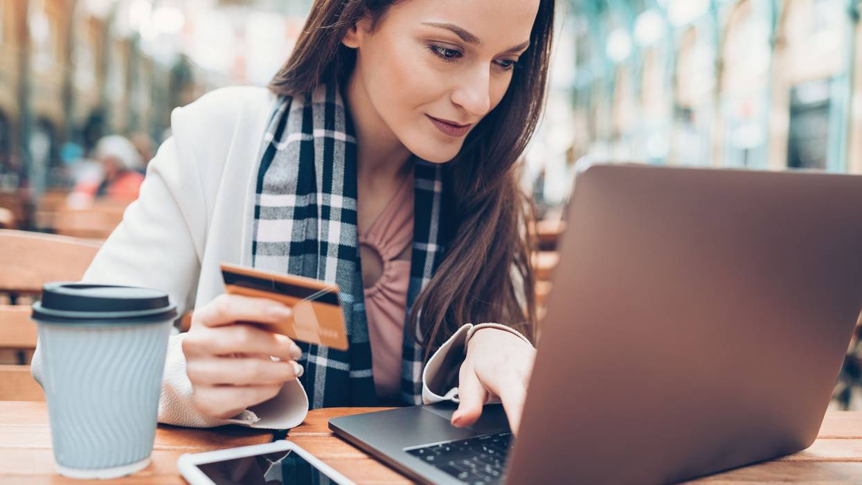 A woman types credit card information on a laptop.