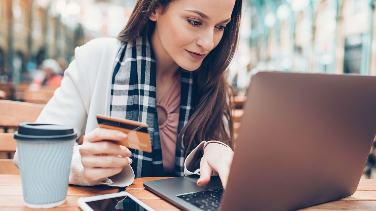 A woman types credit card information on a laptop.