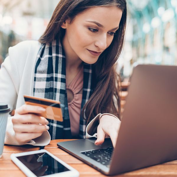 A woman types credit card information on a laptop.