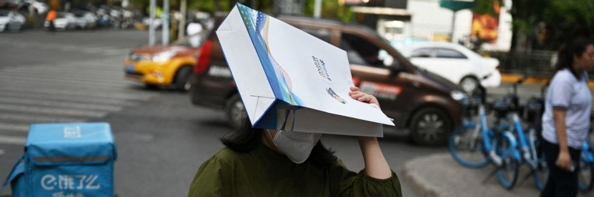 A woman uses a bag to hide from a Beijing heatwave.