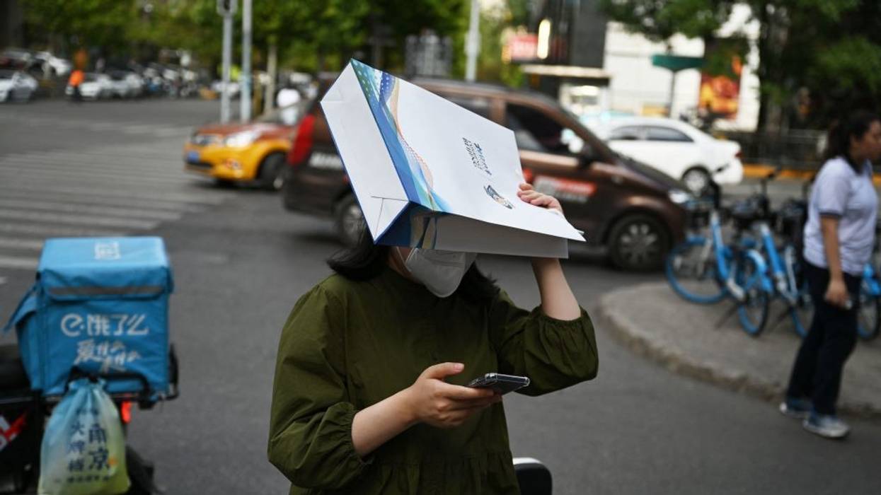 A woman uses a bag to hide from a Beijing heatwave.