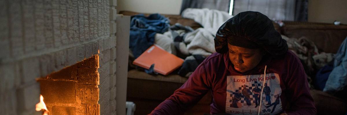 A woman uses a fire to provide heat in her home