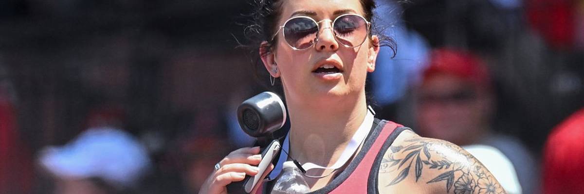 A woman uses a small battery-powered fan to try to stay cool