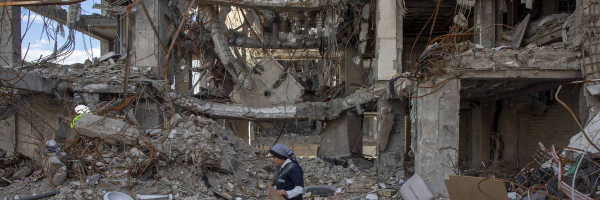 A woman walks among buildings destroyed in a joint attack by Israel and the United States in Iran