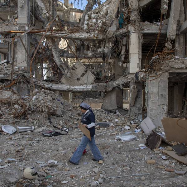 A woman walks among buildings destroyed in a joint attack by Israel and the United States in Iran