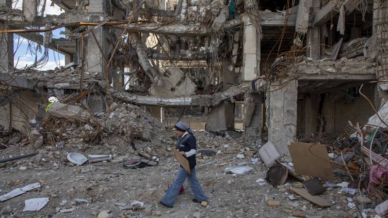 A woman walks among buildings destroyed in a joint attack by Israel and the United States in Iran