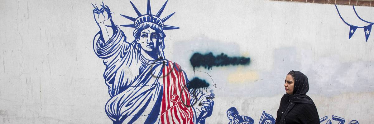 A woman walks in front of an anti-American mural in Iran.