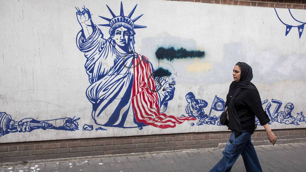 A woman walks in front of an anti-American mural in Iran.