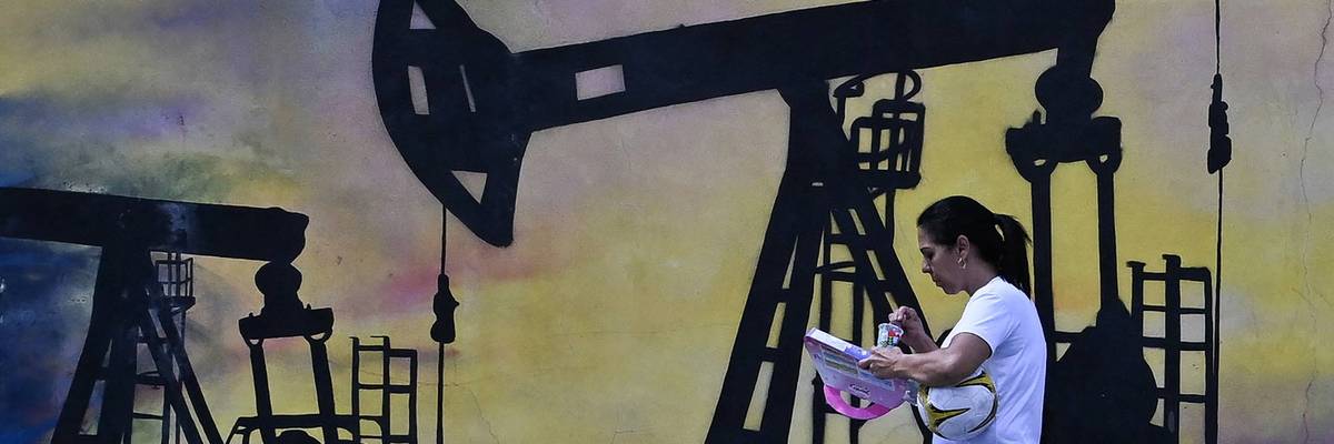 A woman walks past a mural of an oil pump in Venezuela.