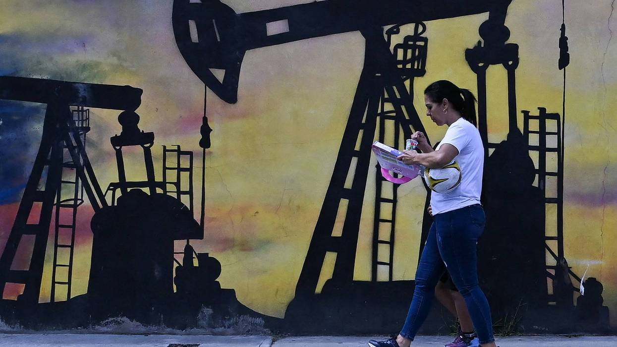 A woman walks past a mural of an oil pump in Venezuela.
