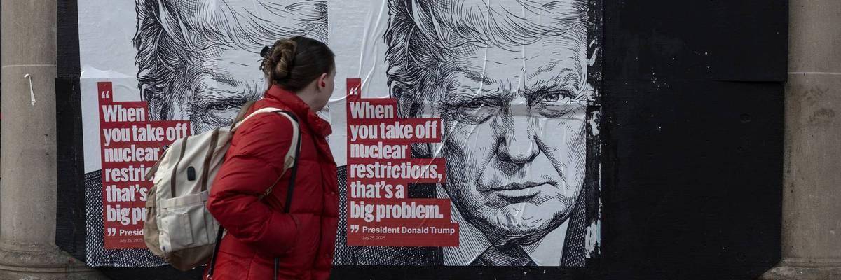 A woman walks past a wall poster that warns of the impending expiration of New START
