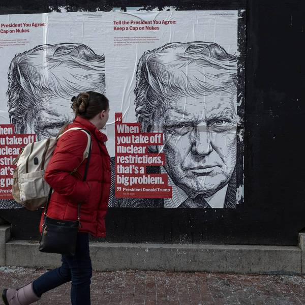 A woman walks past a wall poster that warns of the impending expiration of New START
