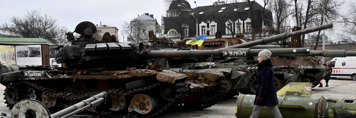 A woman walks past destroyed Russian military vehicles