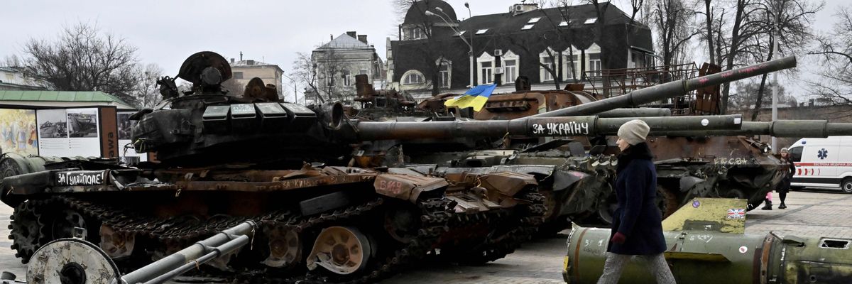 A woman walks past destroyed Russian military vehicles