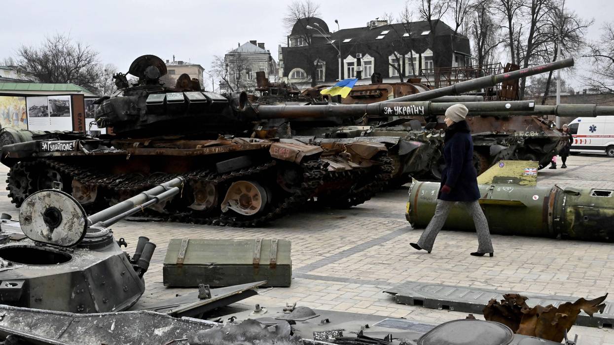 A woman walks past destroyed Russian military vehicles