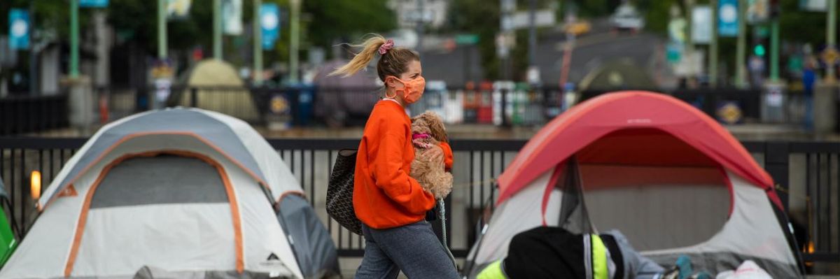 A woman walks past tents used by people experiencing homelessness in Washington, D.C.