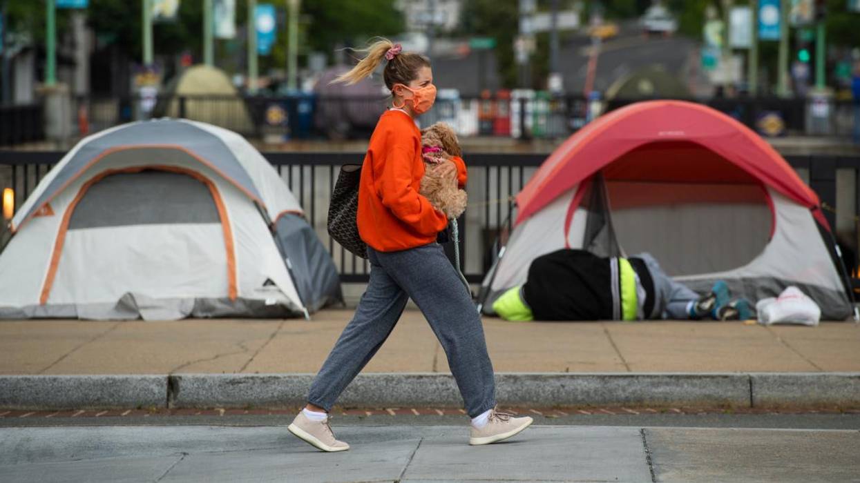 A woman walks past tents used by people experiencing homelessness in Washington, D.C.