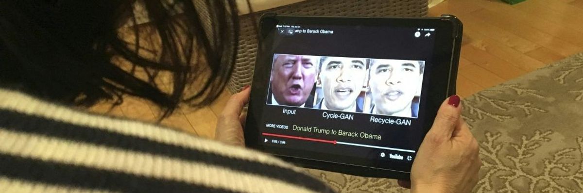 A woman watches a deepfake of Trump and Obama on a hand-held screen.