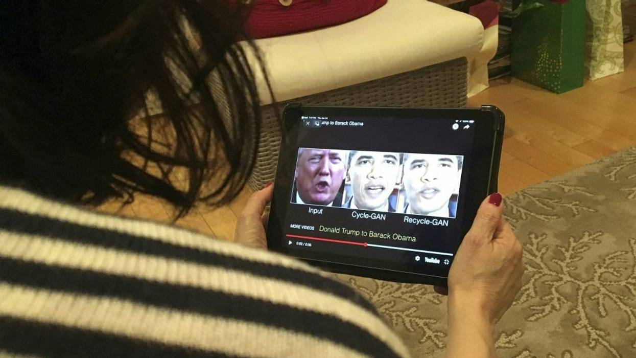 A woman watches a deepfake of Trump and Obama on a hand-held screen.