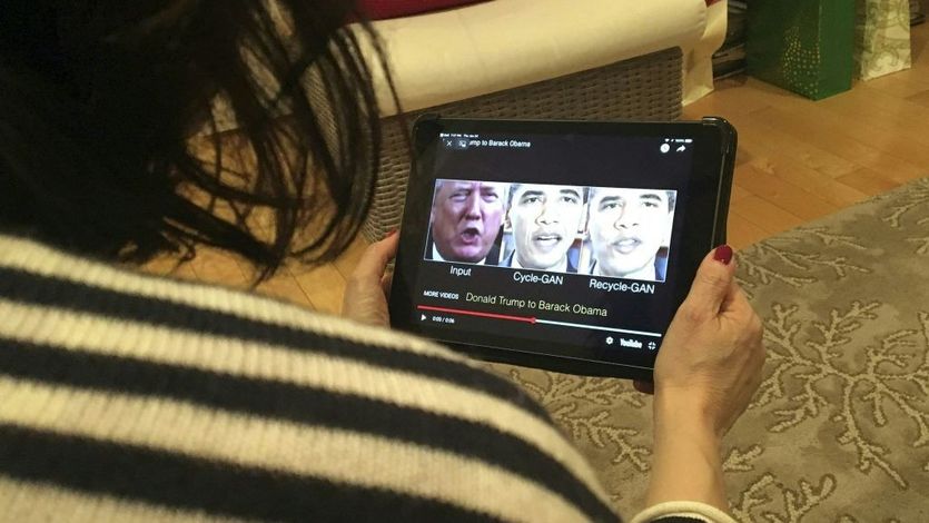 A woman watches a deepfake of Trump and Obama