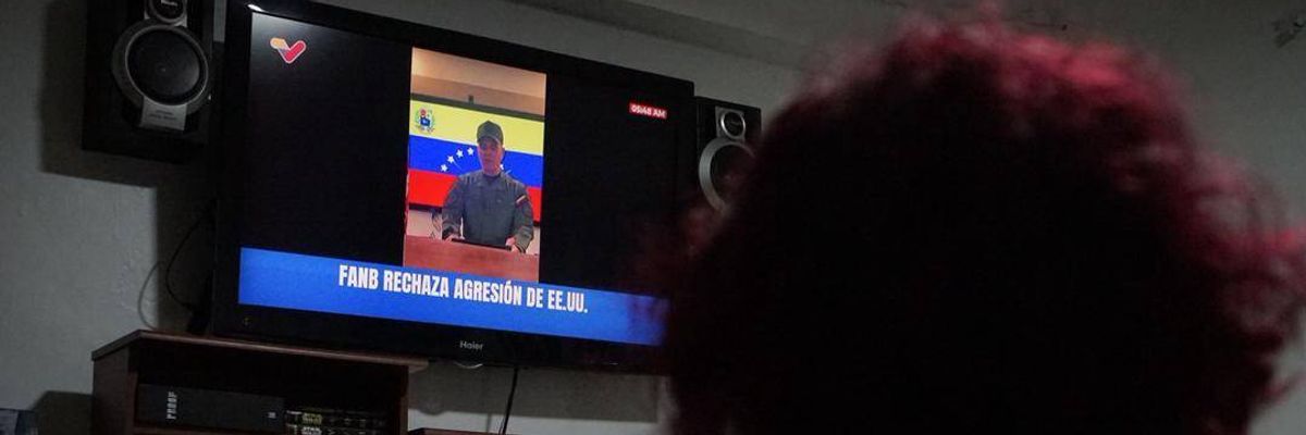 A woman watches a public television broadcast by Venezuelan Defense Minister Vladimir Padrino