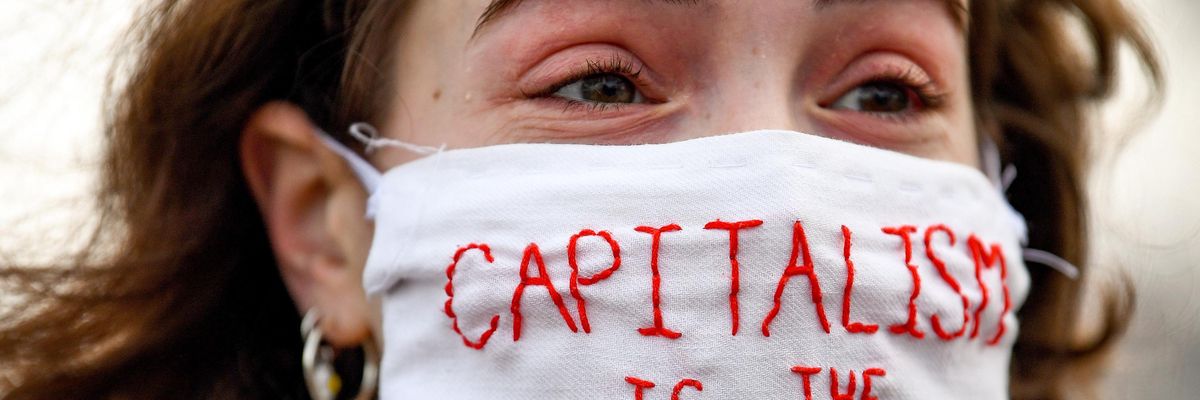 A woman wearing a mask saying, "Capitalism is the virus."
