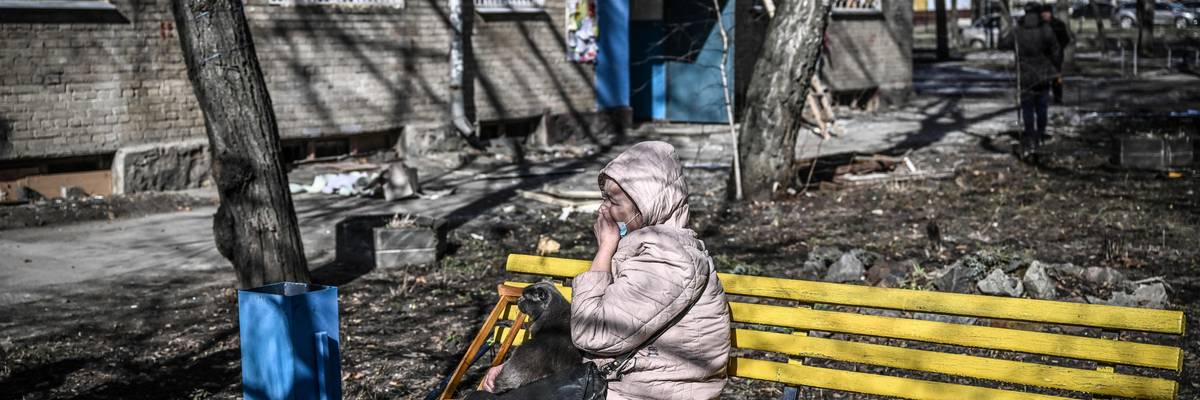 A woman weeps as she sits outside a building that was damaged by bombing in the eastern Ukraine town of Kharkiv on February 24, 2022.
