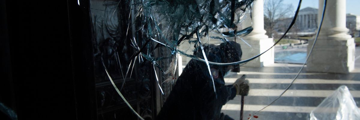 A worker cleans broken glass from one of the entrances to the U.S. Capitol the day after a pro-Trump mob broke into the building on January 6, 2021. (Photo: Brendan Smialowski/AFP via Getty Images)