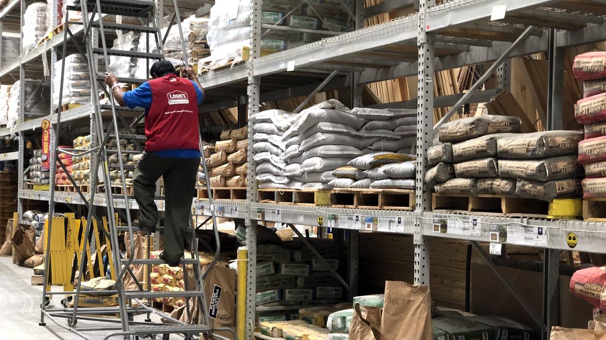 A worker climbs a ladder at Lowe's.