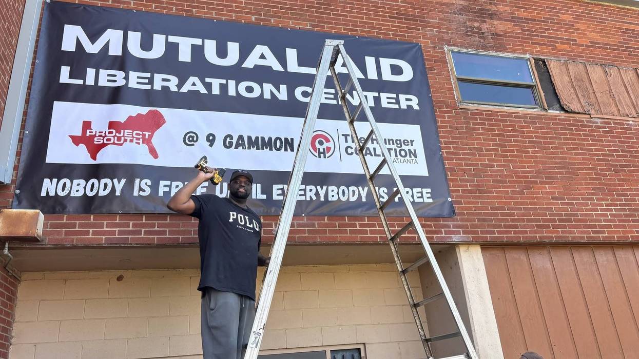 A worker hangs a sign reading, "Mutual Aid Liberation Center."