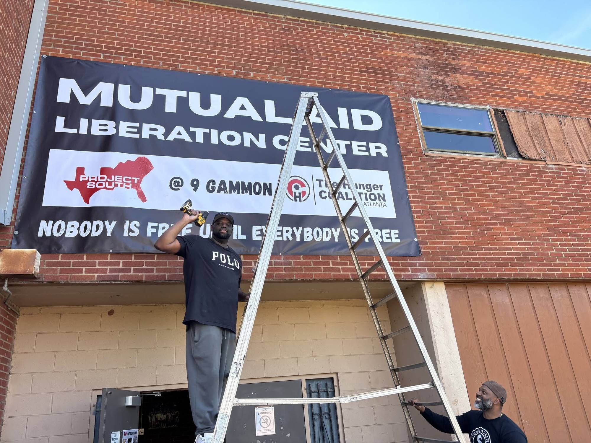 A worker hangs a sign reading, "Mutual Aid Liberation Center."