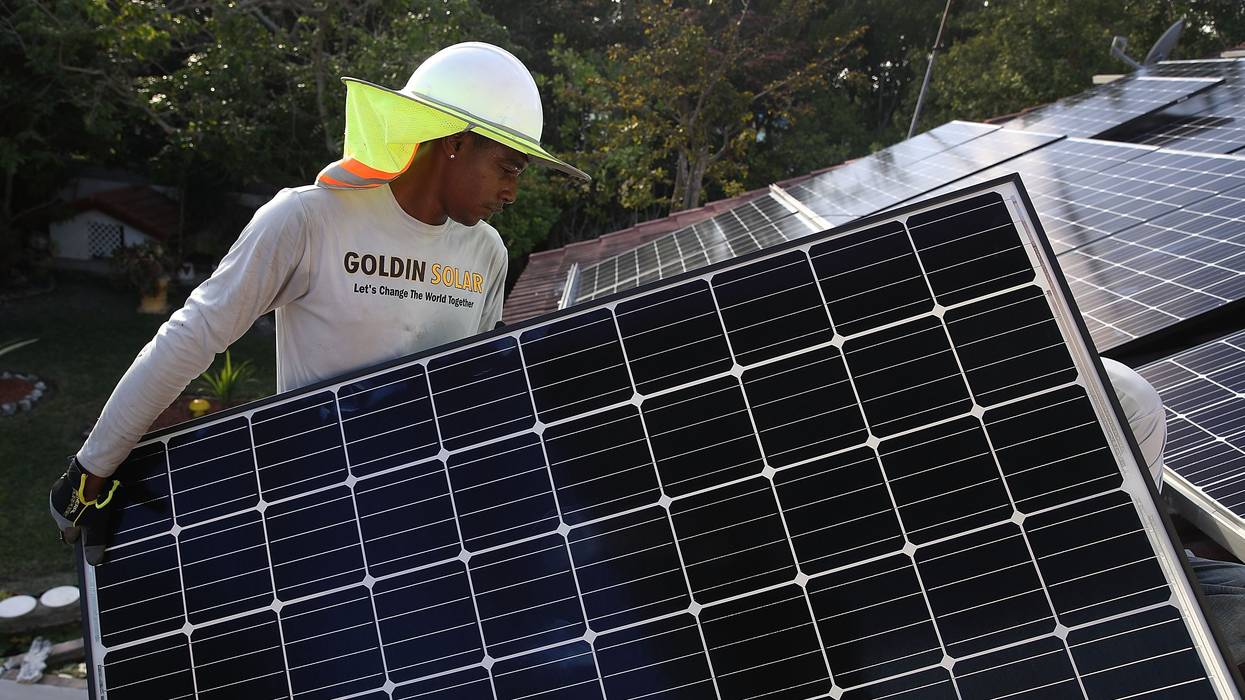A worker installs solar panels.