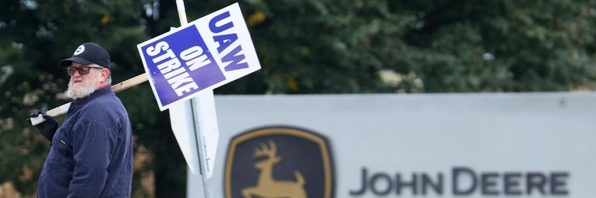 A worker pickets with a sign over his shoulder.