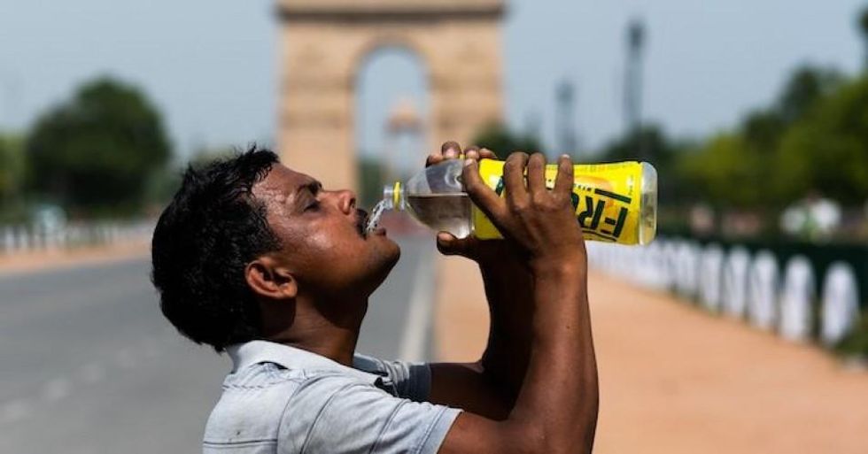 A worker quenches his thirst with water from a bottle taking a break from cleaning weeds from a park near India Gate amid rising temperatures in New Delhi on May 27, 2020. India is wilting under a heatwave, with the temperature in places reaching 50 degrees Celsius (122 degrees Fahrenheit) and the capital enduring its hottest May day in nearly two decades. (Photo: Jewel Samad/AFP via Getty Images)