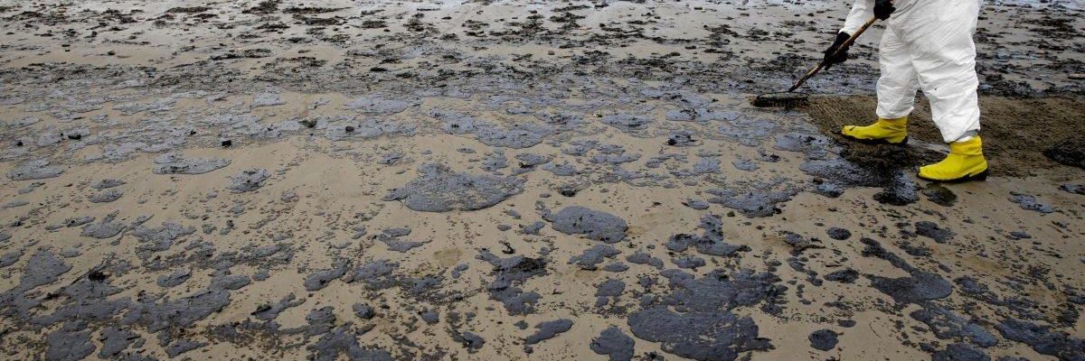 A worker removes oil from the sand at Refugio State Beach
