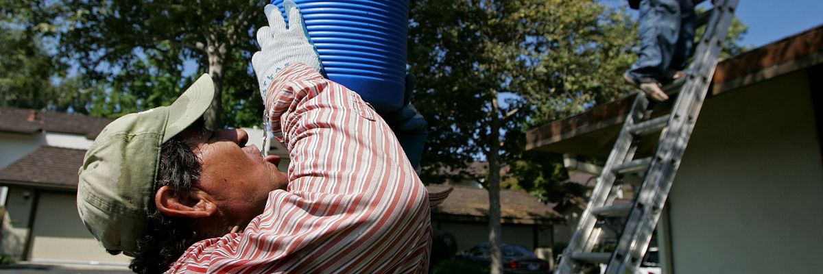 A worker with the Moran Roofing Company takes a drink during a break