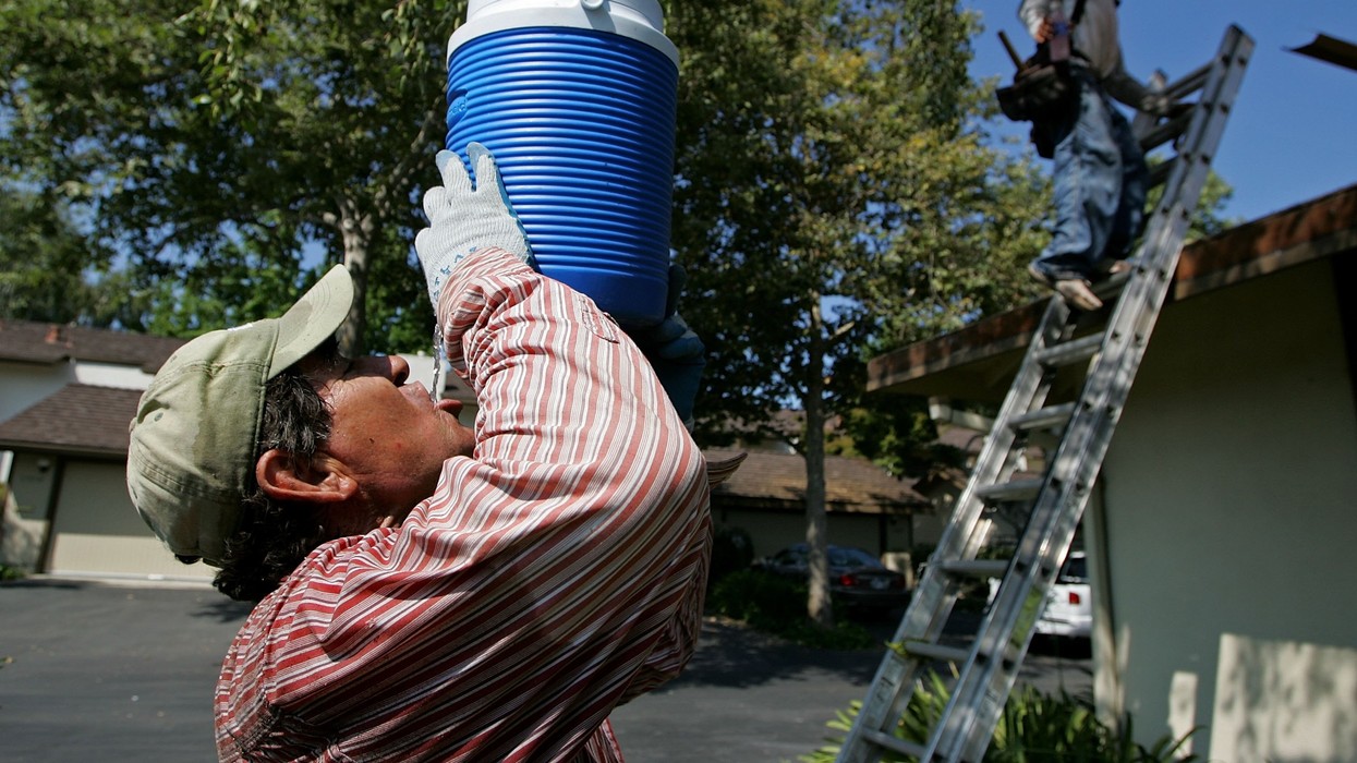 A worker with the Moran Roofing Company takes a drink during a break