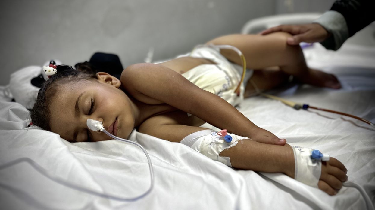 A wounded 2 year old lies on a bed in Gaza.