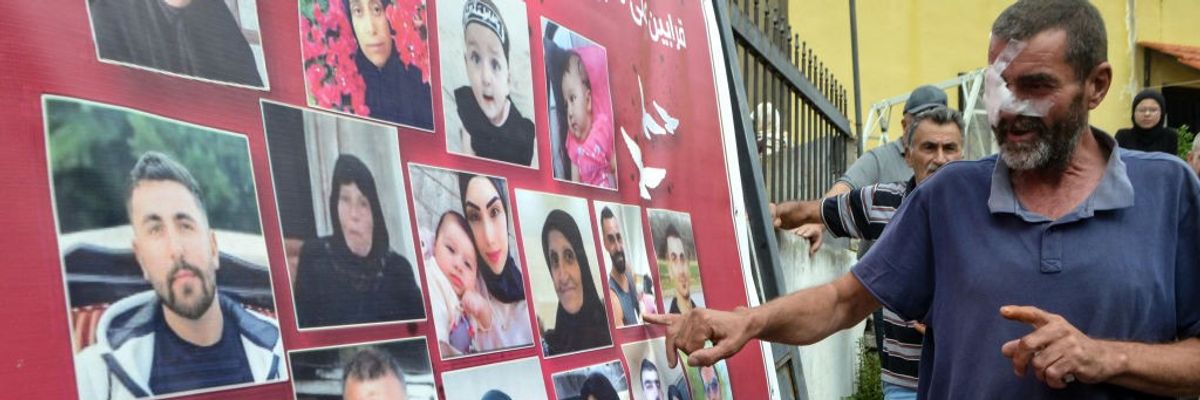 A wounded Lebanese man points to a photo montage of victims of an Israeli airstrike