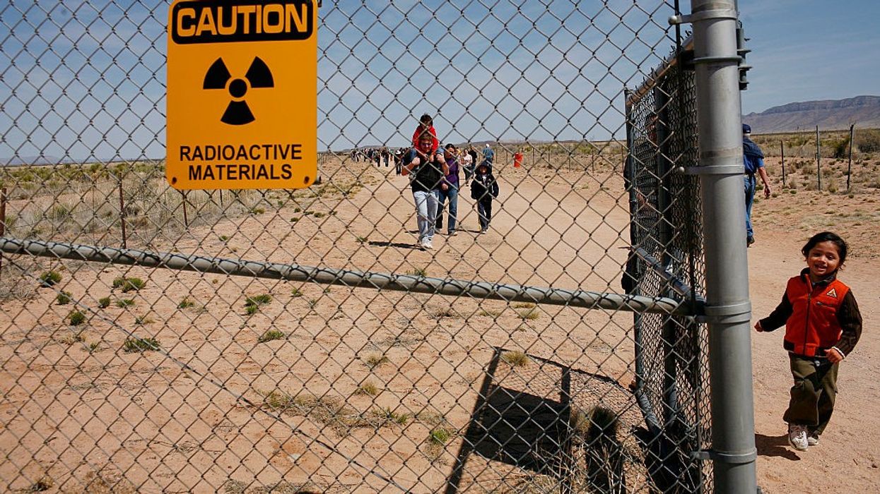 A yellow sign saying, "Caution: Radioactive Materials" is attached to a chain-linked fence at the Trinity Site.
