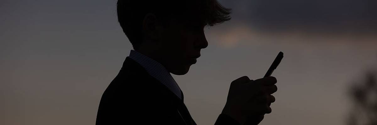 A young boy looks at a phone.