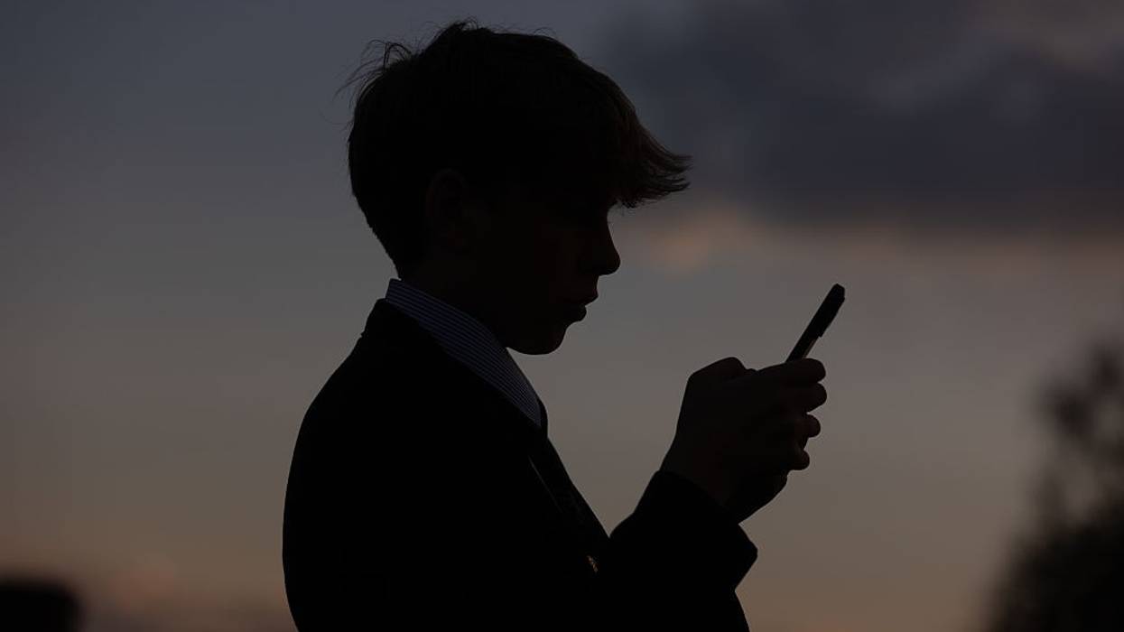 A young boy looks at a phone.