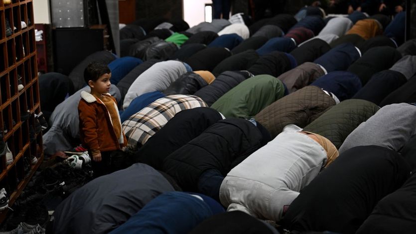 A young boy watches as people pray during a funeral service for 6-year-old