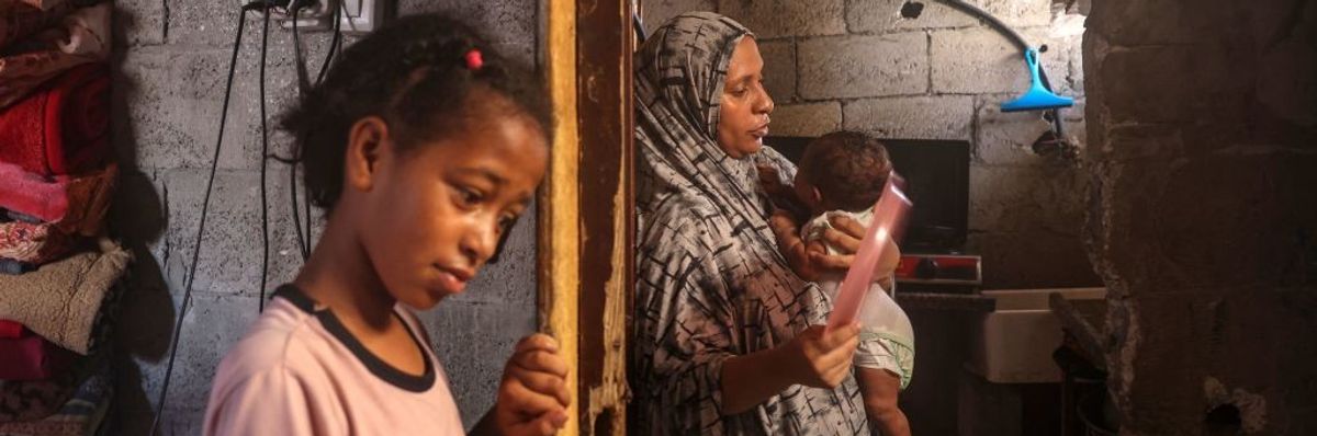 A young girl, mother, and baby look unhappy in a Palestinian heatwave.