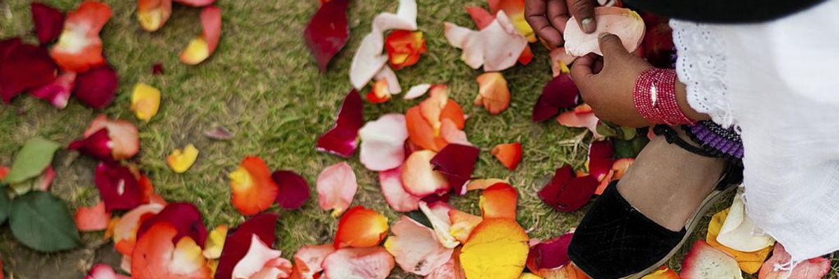 A young girl plays with colorful rose petals during the Inti Raymi celebration in the village of Pesillo, Ecuador