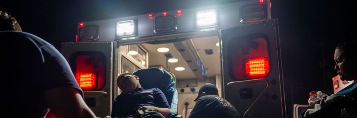 A young man with dehydration is on a stretcher loaded into am ambulance.