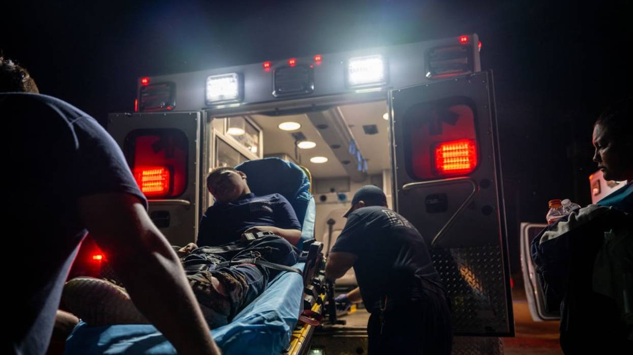 A young man with dehydration is on a stretcher loaded into am ambulance.