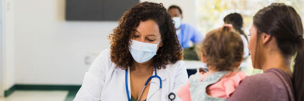 A young mother talks to a doctor as she takes notes.