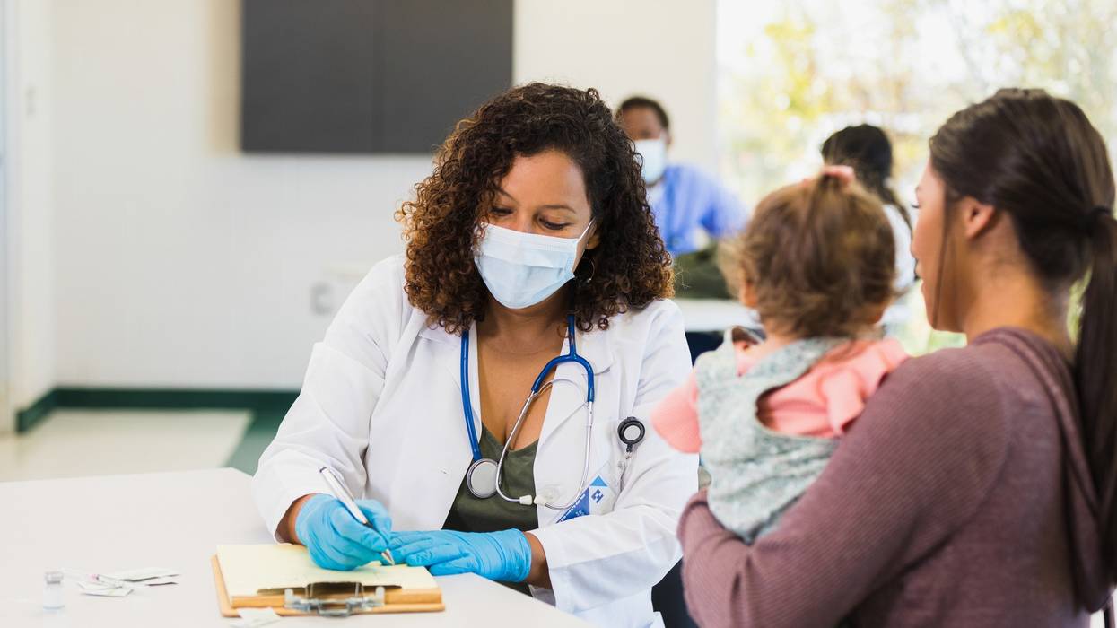 A young mother talks to a doctor as she takes notes.