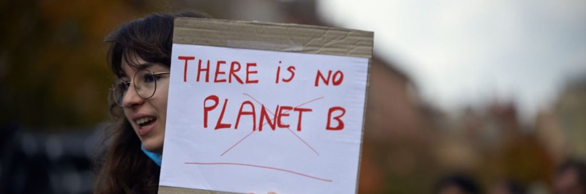 A young woman holds a sheet 'There is no Planet B'.